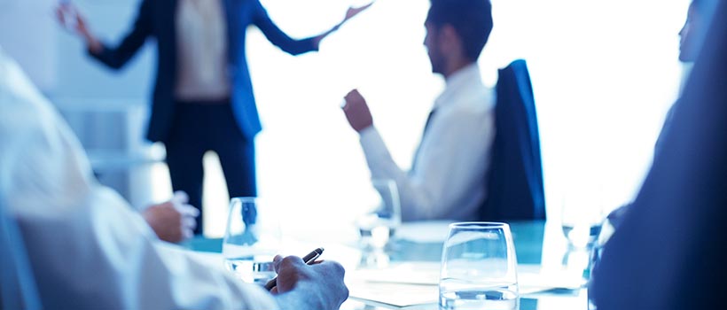 An employee in a conference room taking notes during a presentation.