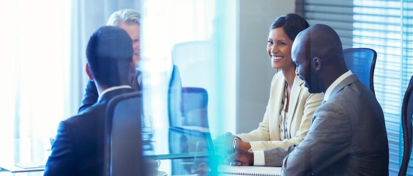 A photo of employees meeting at a table in a conference room.