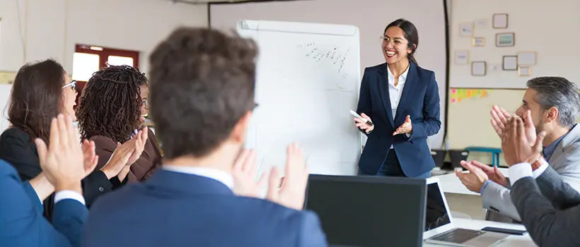 A photo of a woman doing a presentation for her coworkers. 