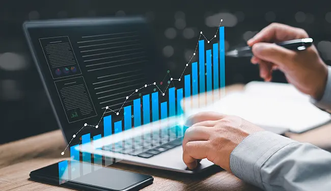 A person working at a laptop with a digital representation of a bar graph.