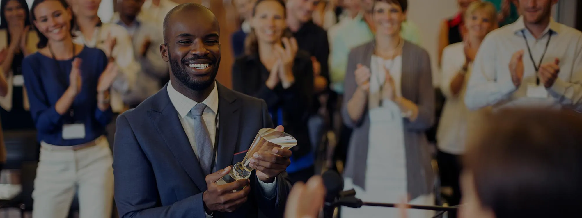 A photo of a man in a crowd receiving a trophy.